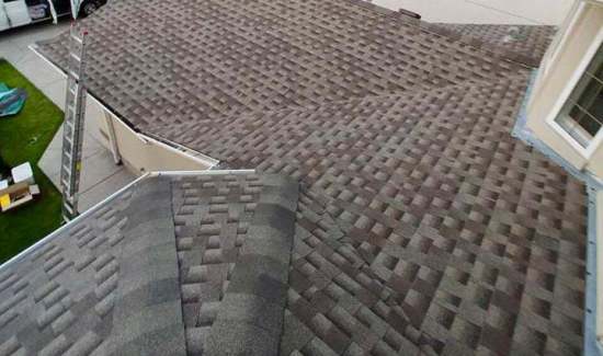 Overhead view of a multi-sloped brown architectural shingle roof installation with ridge capping and flashing by AKRoN Roofing.