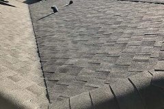 Close-up view of grey dimensional asphalt shingles, roof valley flashing, and hip ridge capping inspected by AKRoN Roofing.