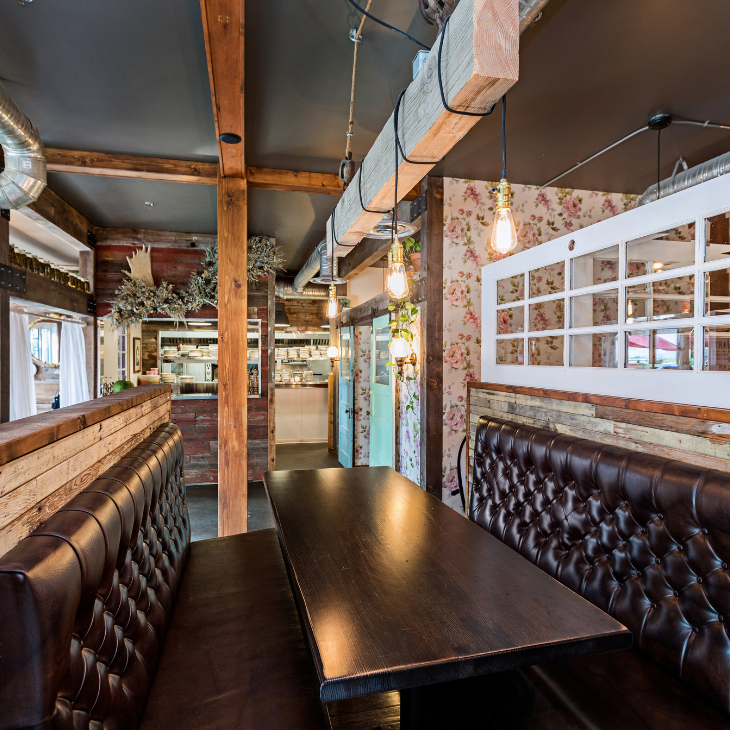Completed restaurant dining room renovation featuring dark tufted leather booth seating, timber beams, and warm pendant lighting completed by restaurant remodelling contractor Belvan Construction